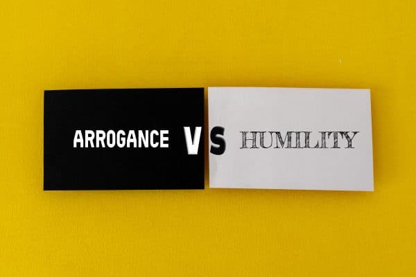 Cards displaying Arrogance vs Humility on a yellow background, illustrating how humility in leadership compares to signs of arrogance.