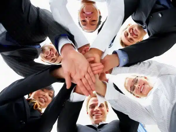 Close-up of corporate team members stacking hands together in a modern office.