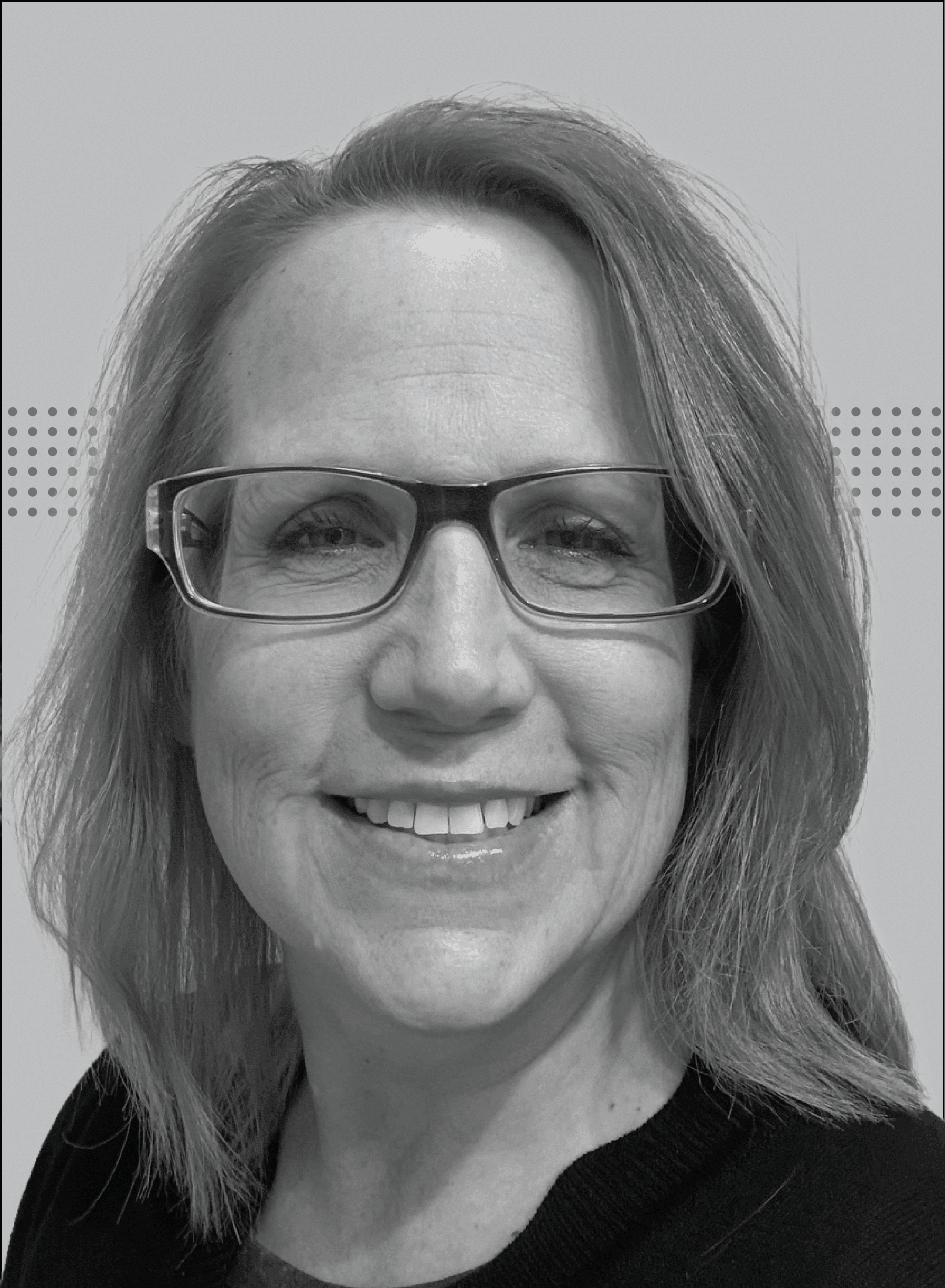 Close-up portrait of a smiling woman with rectangular glasses, grayscale photo.